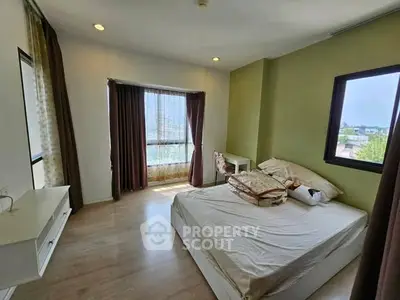 Spacious bedroom with large windows and natural light in modern apartment.