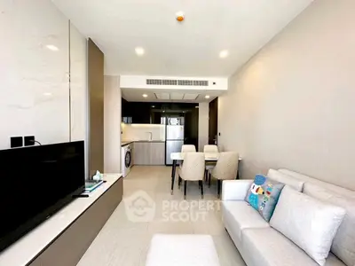 Modern living room with open kitchen, featuring sleek furniture and bright lighting.
