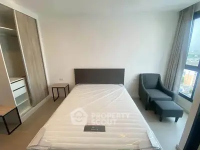 Modern bedroom with minimalist design and large window offering city views.