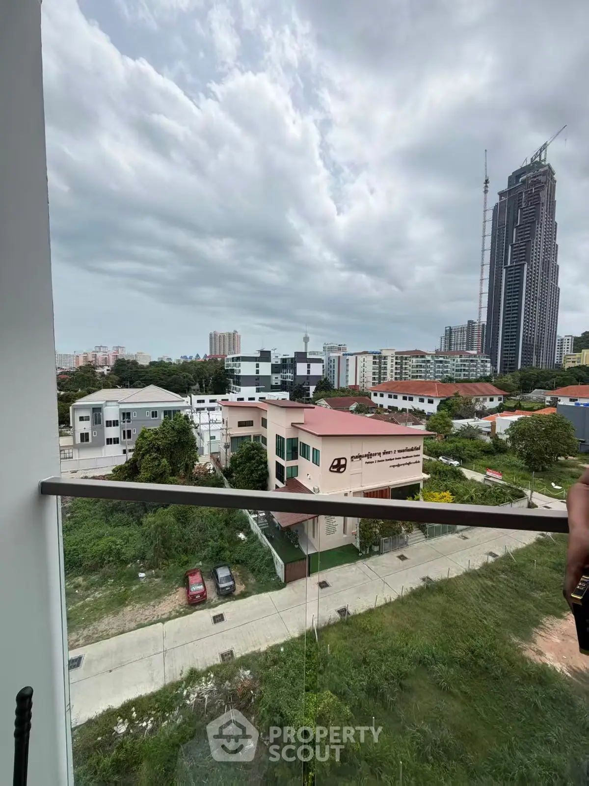 Stunning cityscape view from a modern balcony with lush greenery and towering skyscrapers.