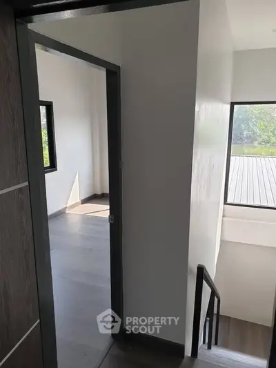 Bright and airy stairway leading to a sunlit room with large windows and modern flooring.