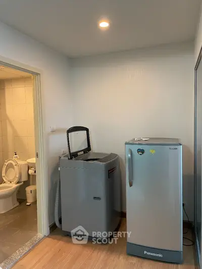 Compact laundry area with washing machine and fridge next to bathroom