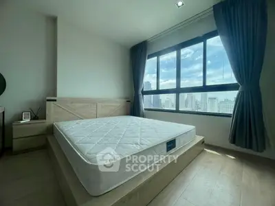 Spacious bedroom with large window offering stunning city views, featuring a modern bed and elegant decor.