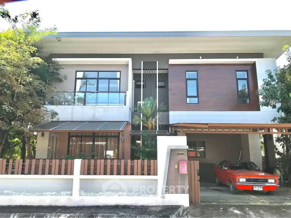 Modern two-story house with carport and lush greenery, perfect for family living.