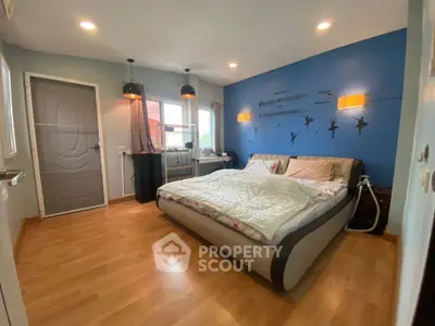 Spacious bedroom with modern decor and large bed, featuring stylish lighting and wooden flooring.