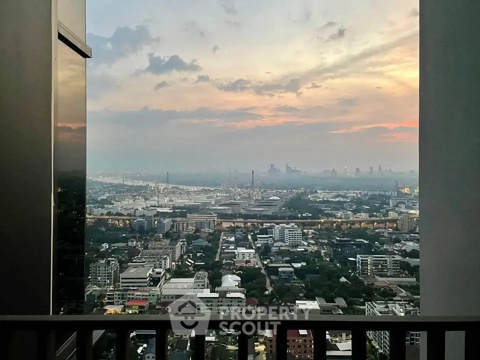 Stunning cityscape view from high-rise balcony at sunset, showcasing urban skyline and vibrant sky.