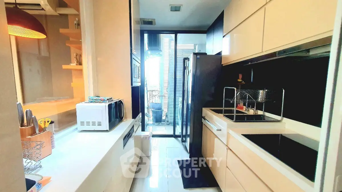 Modern kitchen with sleek cabinetry and glass door leading to balcony