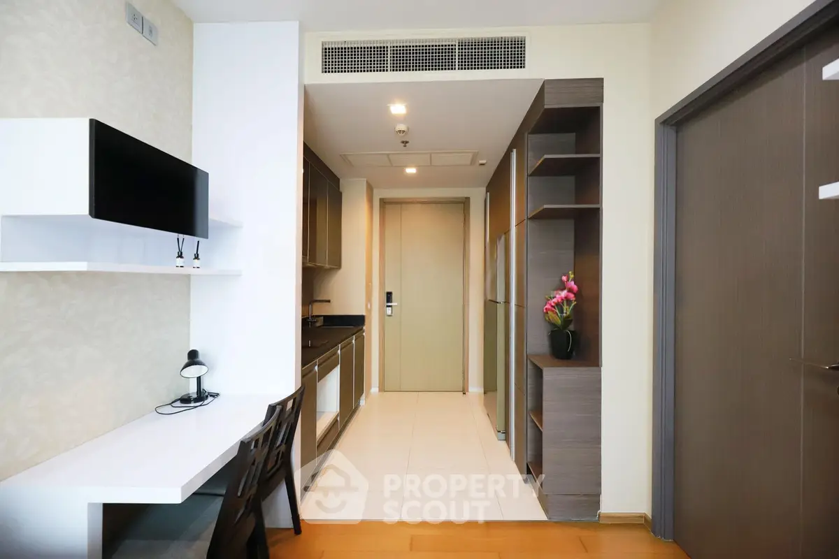 Modern apartment interior with sleek kitchen and study area, featuring contemporary design and efficient use of space.