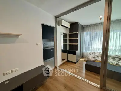 Modern apartment interior with bedroom and kitchen, featuring wooden flooring and large windows.