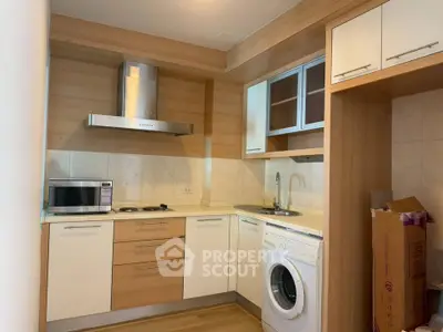 Modern kitchen with wooden cabinets, washing machine, and microwave in compact layout.