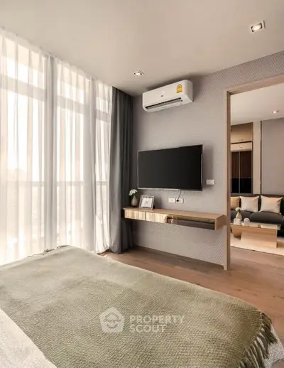 Modern bedroom with large windows, wall-mounted TV, and stylish decor in a contemporary apartment.