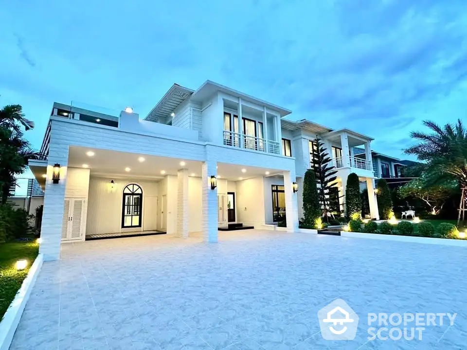 Luxurious modern villa with spacious driveway and elegant exterior lighting.