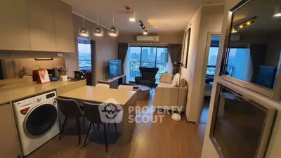 Modern open-plan living room with city view, featuring sleek kitchen and cozy seating area.