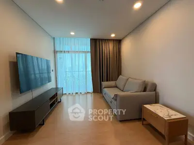 Modern living room with sleek TV setup and cozy sofa in bright apartment.