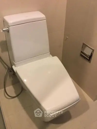 Modern bathroom with sleek toilet design and beige tiles, perfect for contemporary homes.