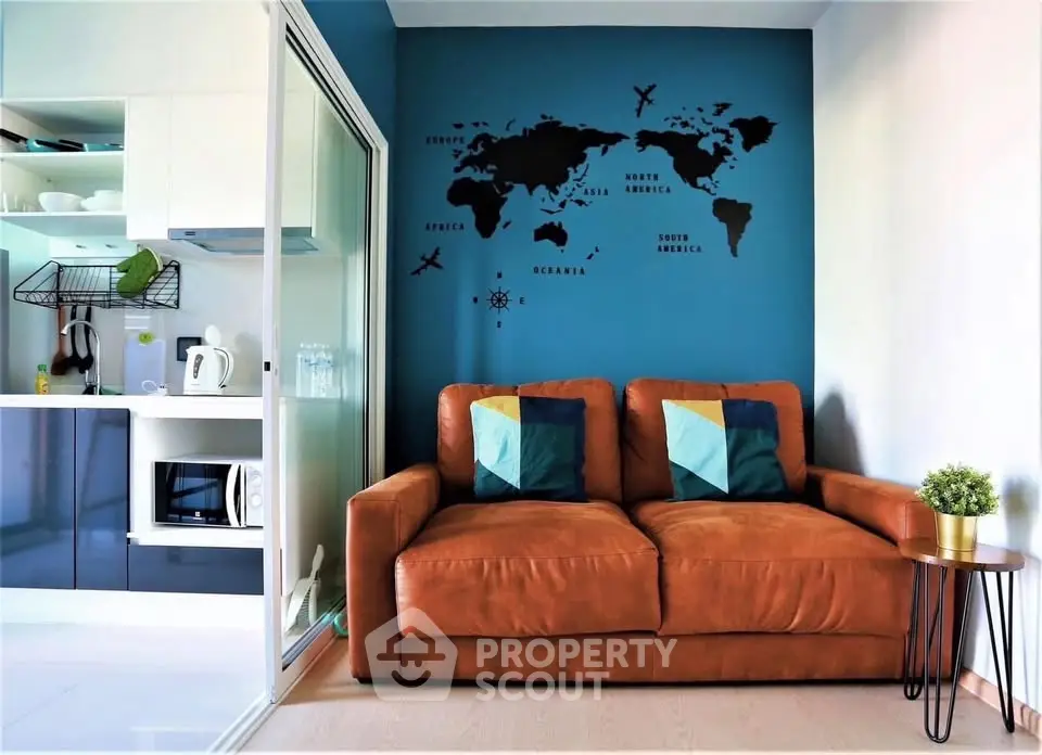 Modern living room with world map wall art and cozy leather sofa, adjacent to sleek kitchen area.