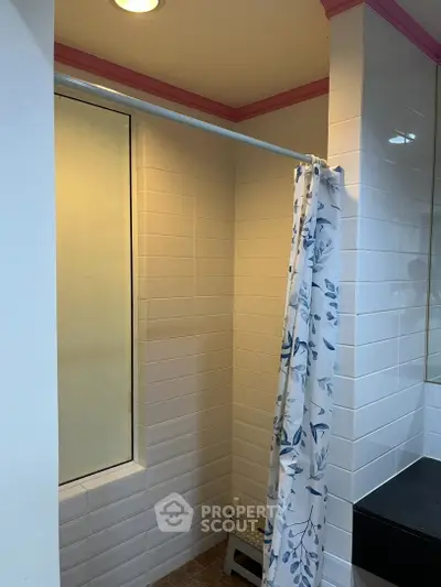 Charming bathroom with tiled walls and floral shower curtain, perfect for a cozy home retreat.