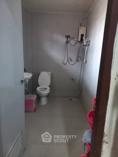 Compact bathroom with shower and toilet in a minimalist design.