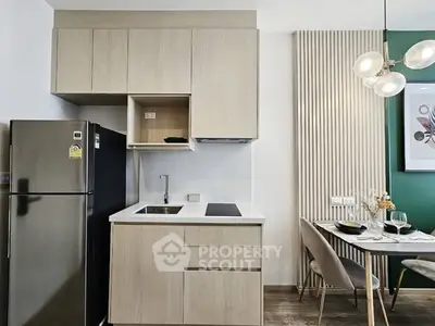 Modern kitchen with sleek cabinets and dining area, featuring contemporary lighting.