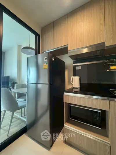 Modern kitchen with stainless steel fridge and microwave in stylish apartment.