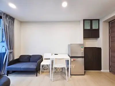Modern living room with sleek furniture and compact kitchen area, perfect for urban living.