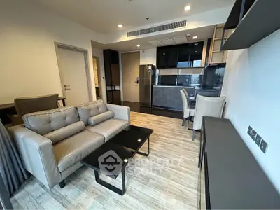 Modern living room with open kitchen, sleek furniture, and wooden flooring in a stylish apartment.