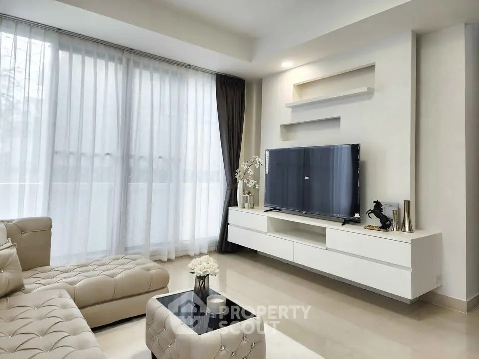 Luxurious modern living room with elegant furniture and large TV, perfect for relaxation.