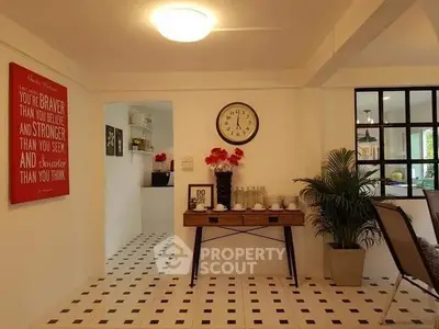 Charming living room with stylish decor and natural light, featuring a wall clock and modern furnishings.