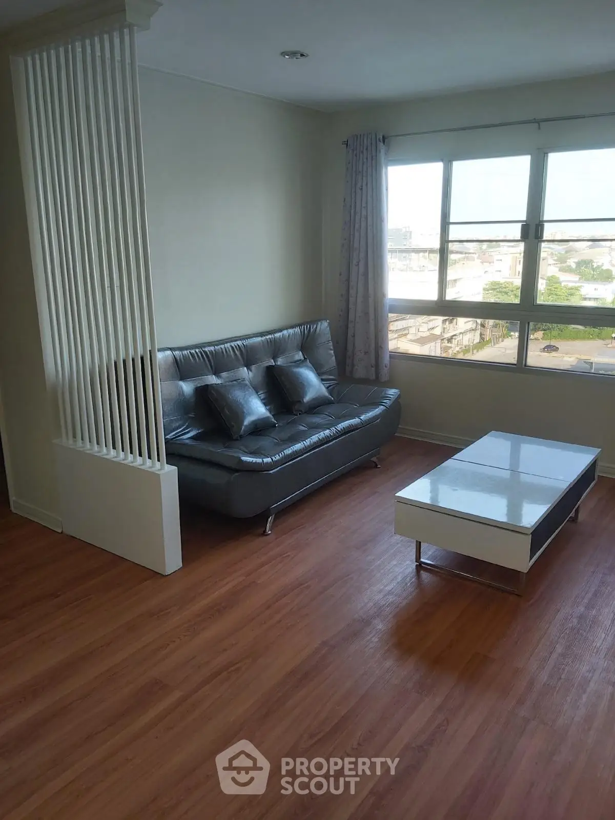Modern living room with sleek sofa and large window offering city view