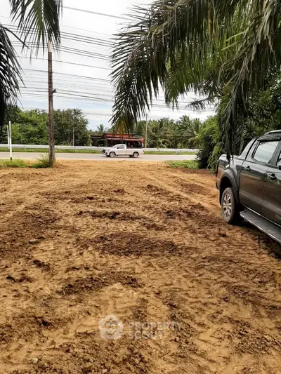 Vacant land plot with potential for development, surrounded by lush greenery and road access.