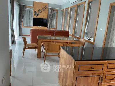 Spacious living room with modern wooden furniture and large windows for natural light.