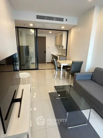 Modern living room with sleek furniture and open kitchen layout in a stylish apartment.