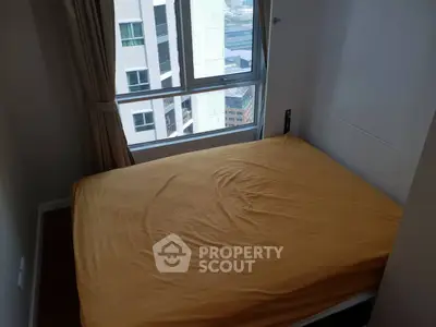 Cozy bedroom with large window offering city views, featuring a neatly made bed and elegant curtains.