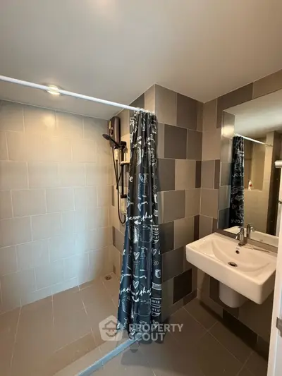 Modern bathroom with sleek tiles and walk-in shower in contemporary apartment.