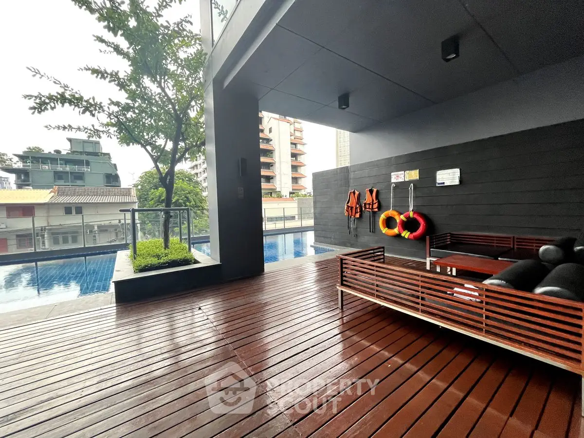 Modern condominium pool area with wooden deck and safety equipment in urban setting.