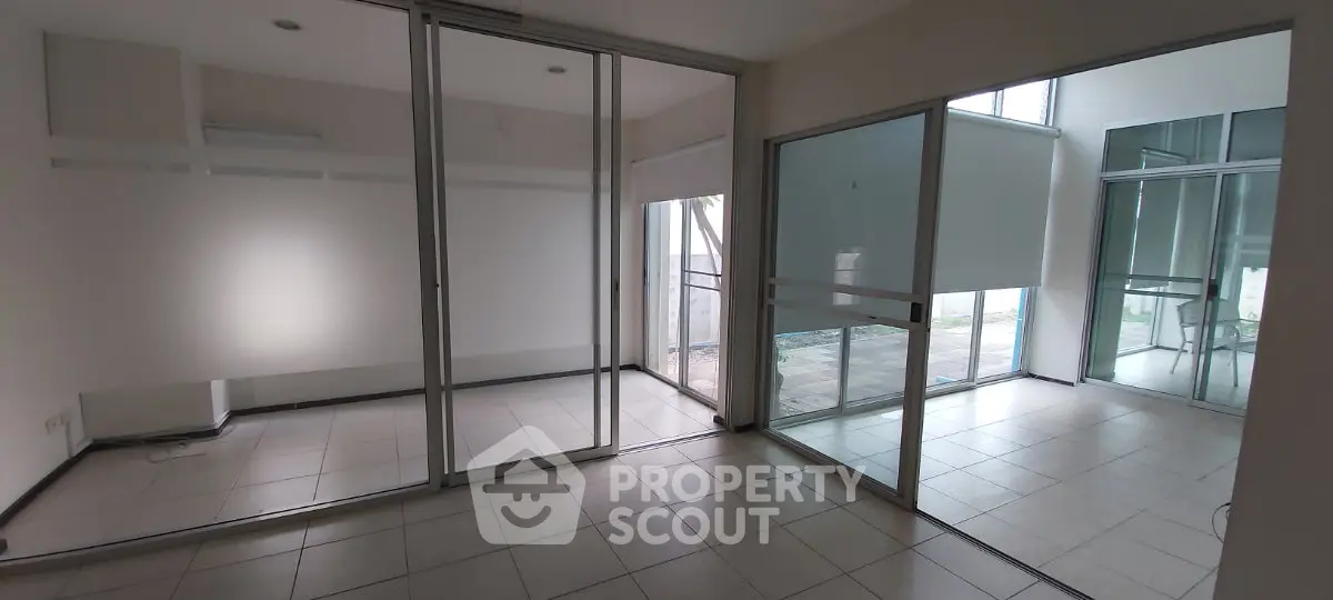Spacious modern interior with glass partitions and tiled flooring, ideal for versatile living or office space.