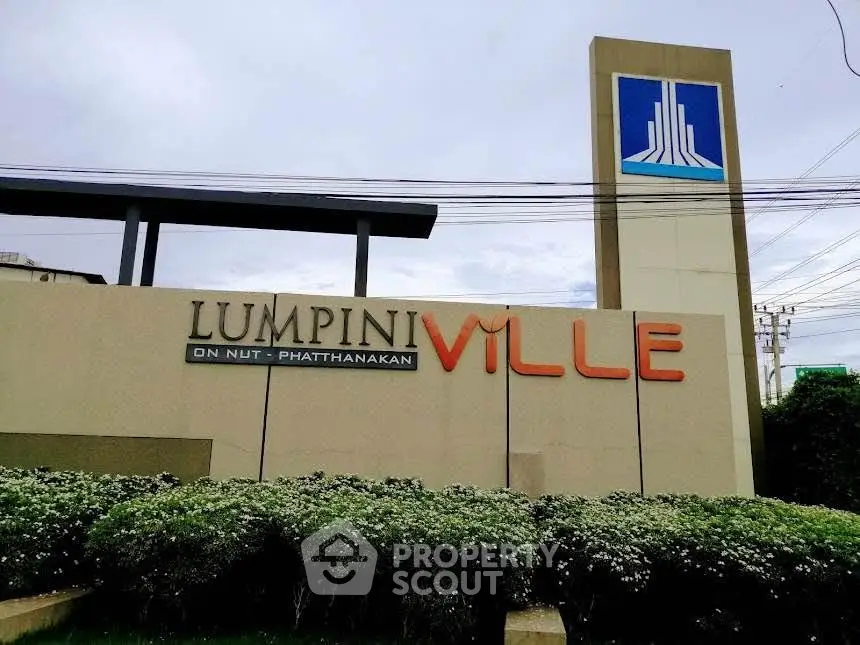 Lumpini Ville entrance with modern signage and lush greenery, showcasing prime real estate location.