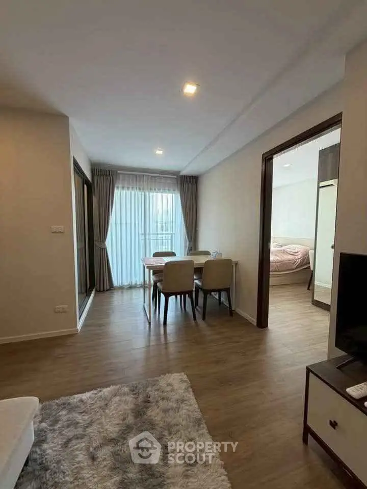 Modern apartment interior with open living and dining area, featuring wooden flooring and natural light.
