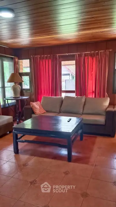 Cozy living room with wooden ceiling, large windows, and comfortable seating.