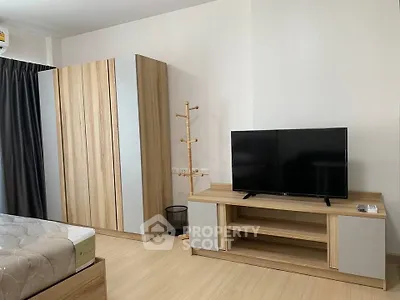 Modern bedroom with wooden furniture and flat-screen TV, perfect for cozy living.