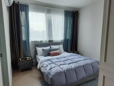 Modern bedroom with cozy bedding and city view, perfect for urban living.