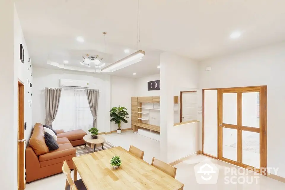 Spacious open-plan living area with ample natural light, modern furniture, and elegant wooden accents, perfect for family gatherings and entertaining guests.