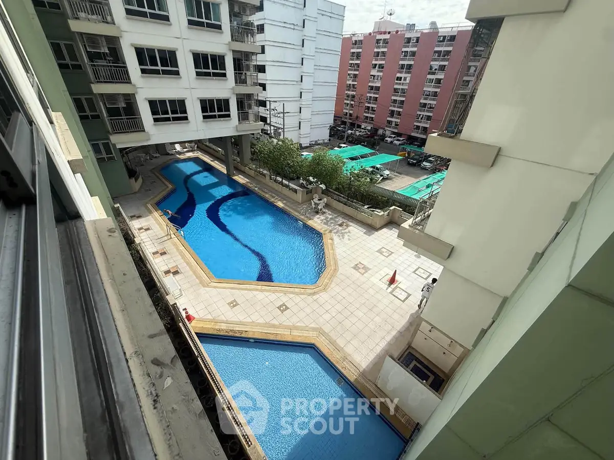 Stunning aerial view of a residential complex with a large swimming pool and surrounding buildings.