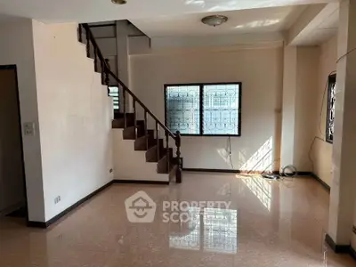 Spacious living room with staircase and natural light, ideal for family gatherings.