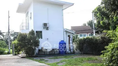 Charming white house with lush greenery and spacious outdoor area, perfect for serene living.