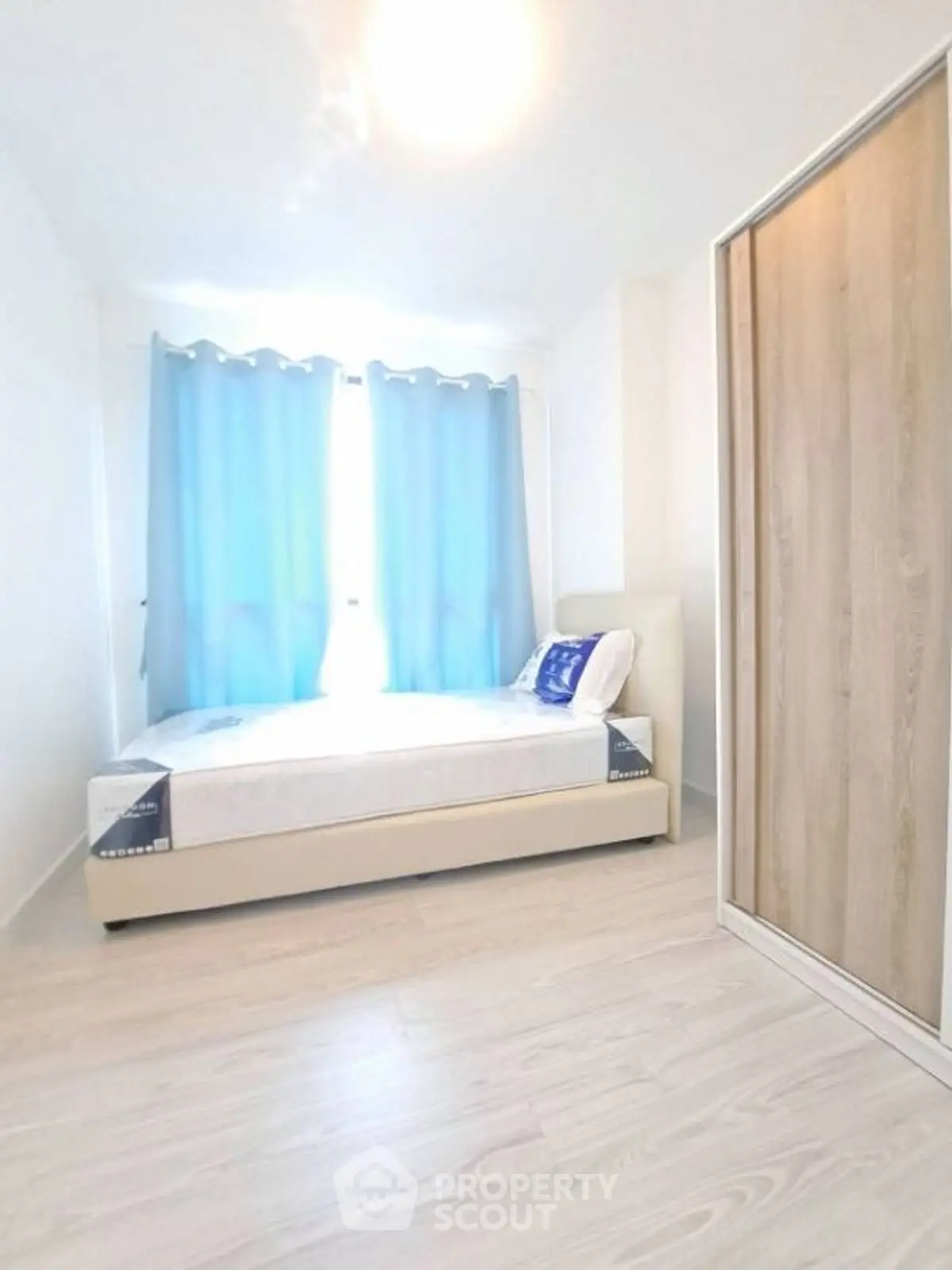 Bright minimalist bedroom with blue curtains and wooden wardrobe