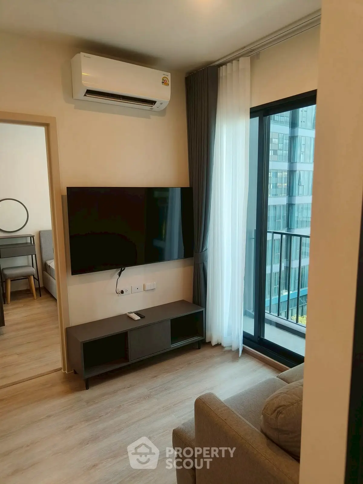 Modern living room with sleek TV setup and balcony view in urban apartment