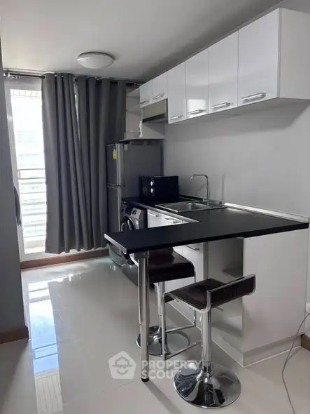 Modern compact kitchen with sleek design and breakfast bar in urban apartment.
