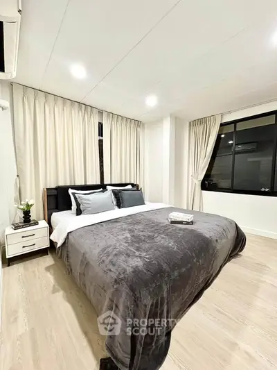 Modern bedroom with cozy bedding and elegant curtains in a stylish apartment.