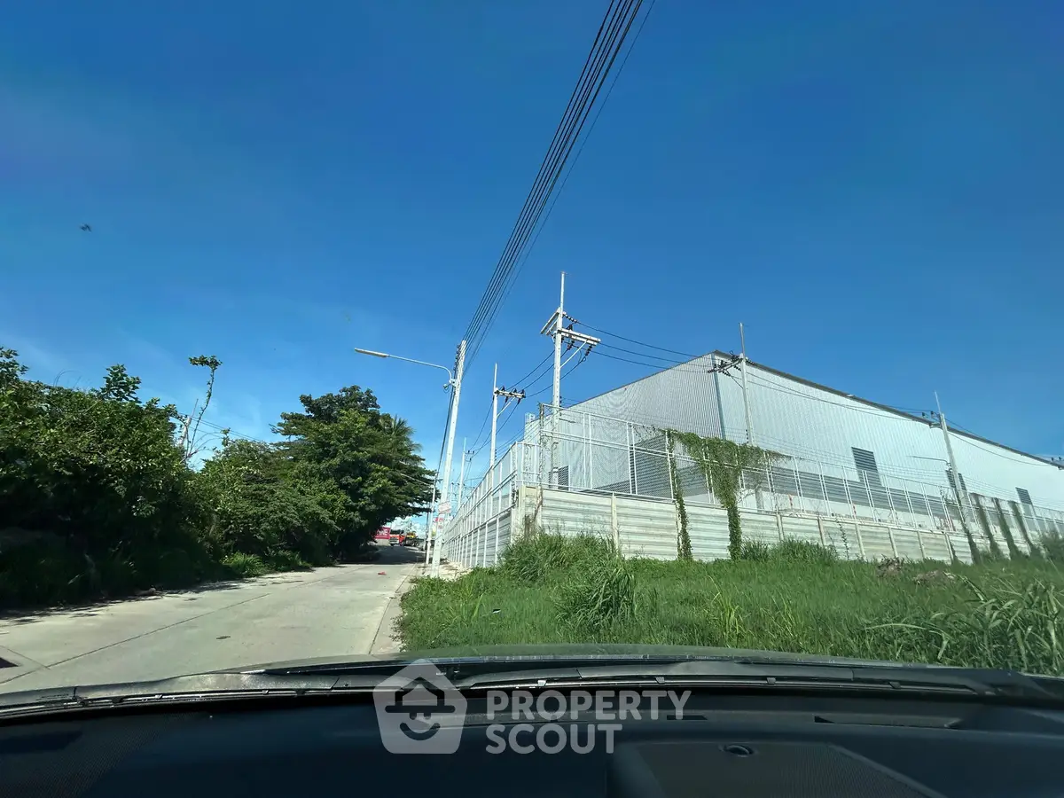 Industrial warehouse exterior with clear blue sky and surrounding greenery, ideal for logistics or manufacturing.